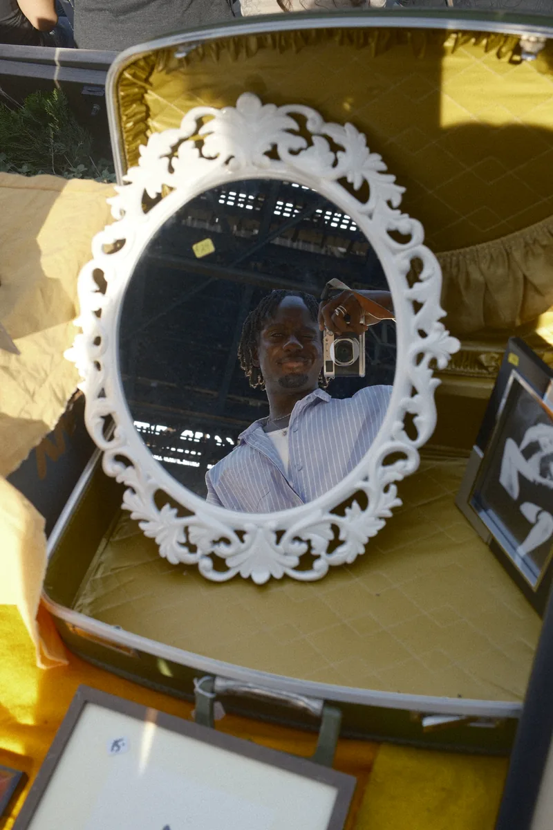 Bassey reflected in an ornate white mirror at a flea market