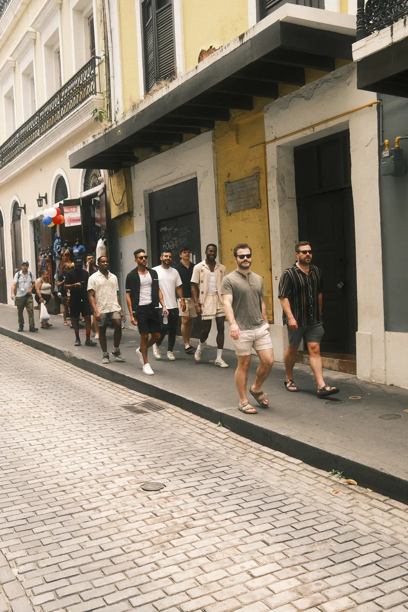 A group of friends walking single file down a sidewalk in Old San Juan