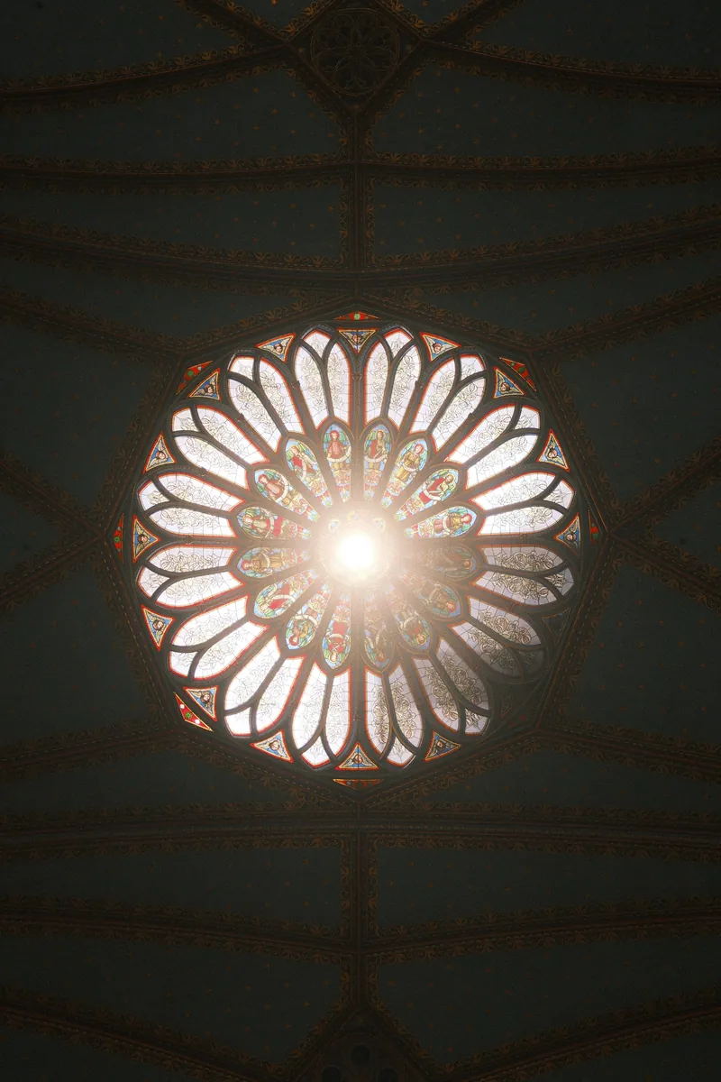 Looking straight up at a glowing rose window in a starred ceiling