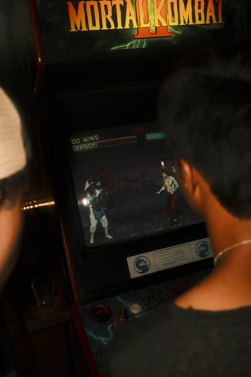 Two friends playing a vintage fighting game at an arcade cabinet
