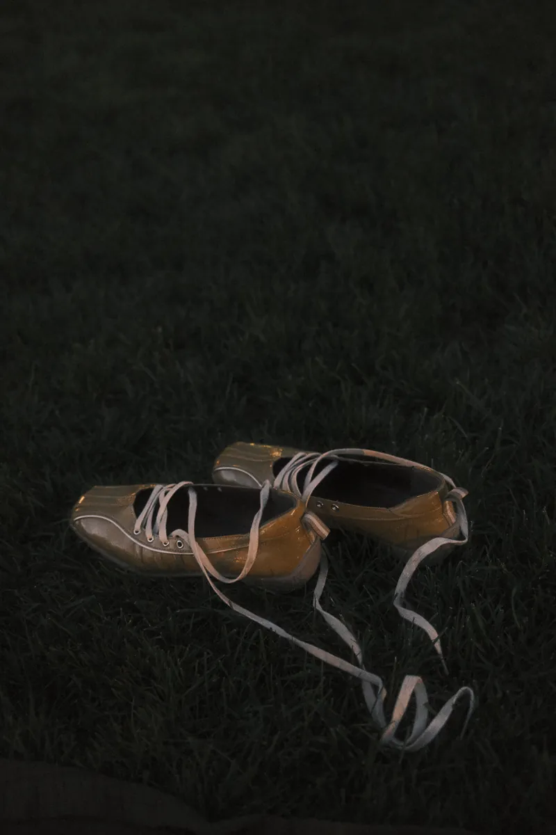 A pair of lace-up flats left on the grass at dusk